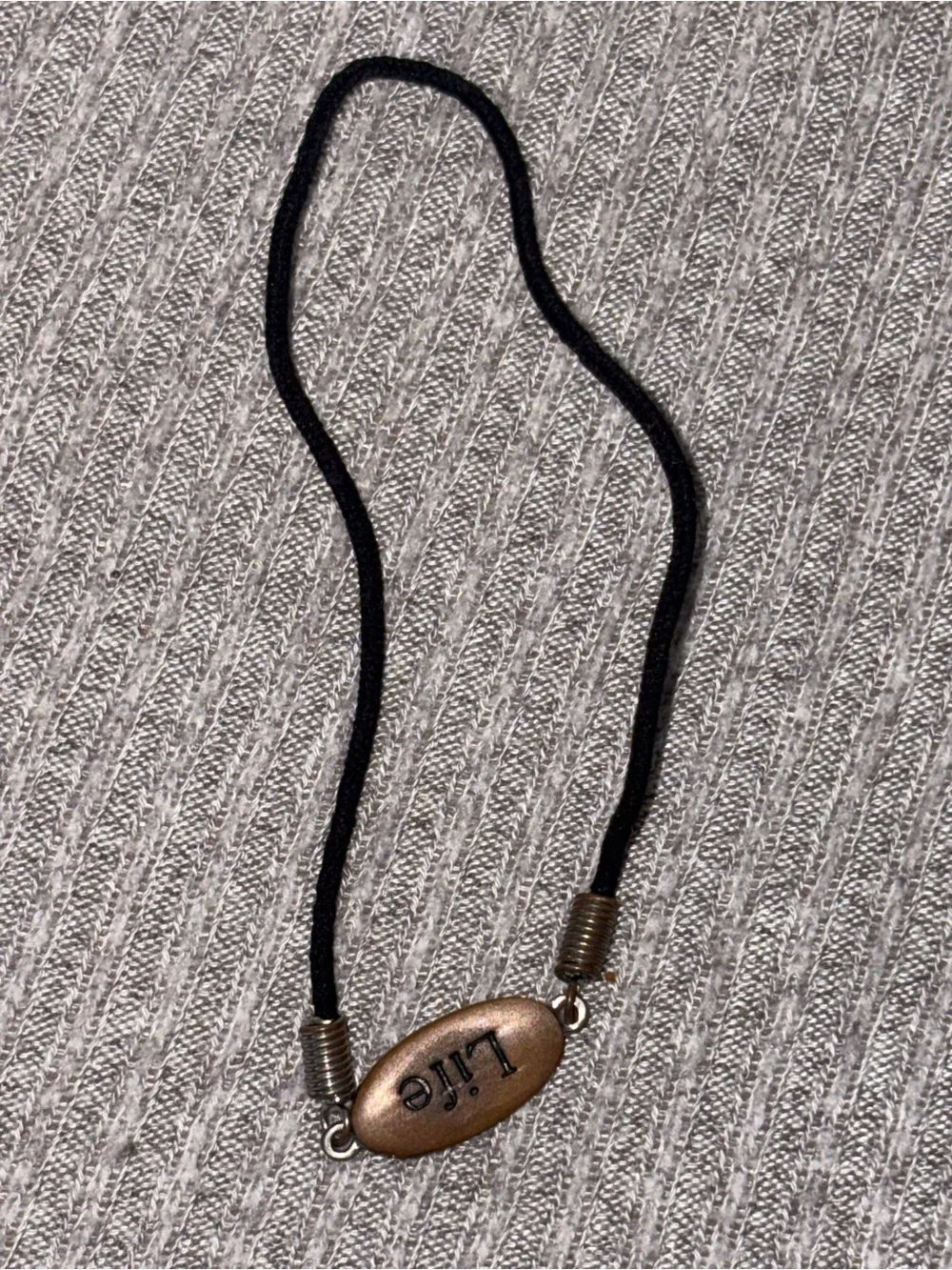Black cord stretch bracelet w brown colored oval “Life” plaque